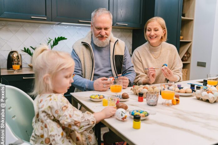 Grandparents with Little Girl Painting Easter Eggs at Table