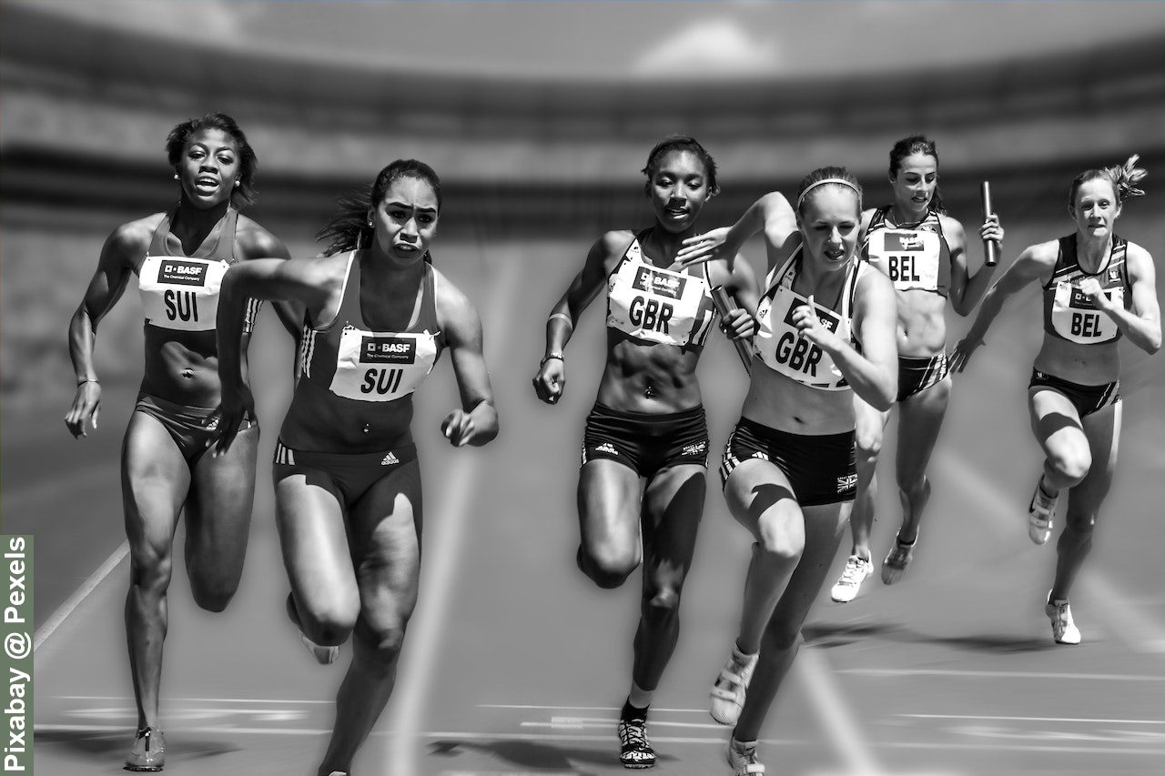 The debate on transgender athletes in sports. Female track athlete doing relay on track, image in black and white