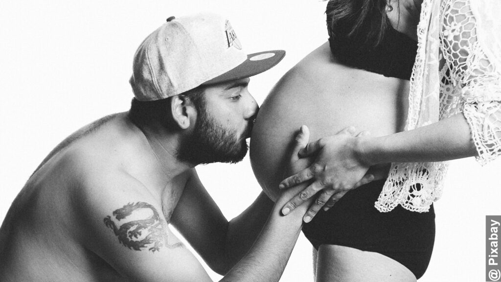 Generational differences between dads and moms grayscale image of man kissing woman's pregnant belly