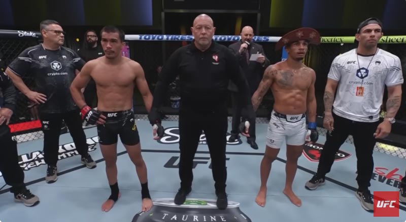 Igor Severino and Andre Lima stand in the UFC octagon with the referee between them, awaiting the official decision following their controversial fight.