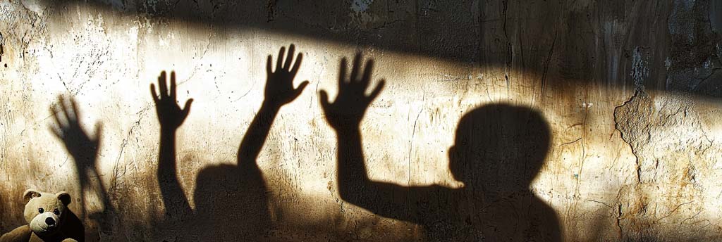 Shadows of raised hands cast against a cracked wall, evoking a sense of distress and tension in the environment, while a lone teddy bear sits quietly in the foreground, symbolising innocence amidst the turmoil of family violence.