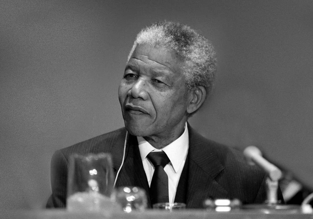 A thoughtful Nelson Mandela in formal attire listening intently during a conference, embodying the dignified leadership that transformed South Africa.